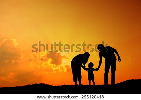 silhouette of father mother and son playing outdoors at sunset