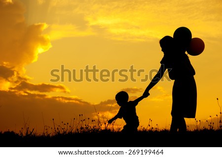 Silhouette of A mother and son playing outdoors at sunset
