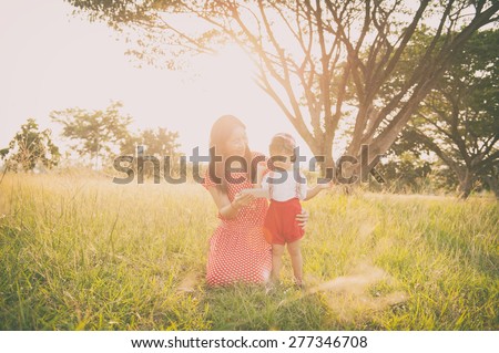Happy family. A mother and son showing smart phone in grass fields outdoors at evening.Vintage Tone and copy space.