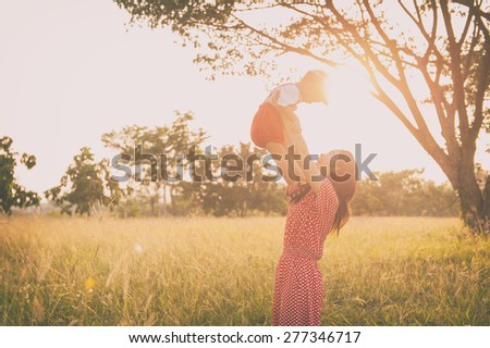 Happy family. A mother and son playing in grass fields outdoors at evening.Vintage Tone and copy space.