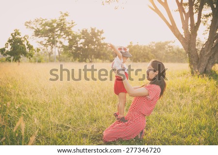 Happy family. A mother and son playing in grass fields outdoors at evening.Vintage Tone and copy space.