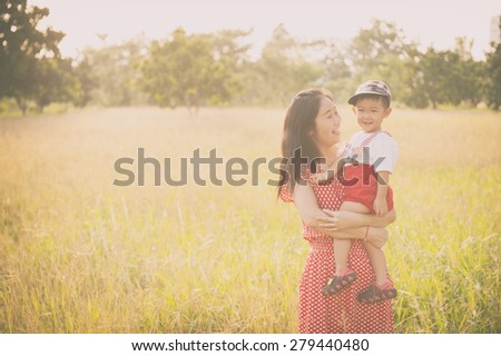 happy family. A mother and son playing in grass fields outdoors at evening.Vintage Tone and copy space