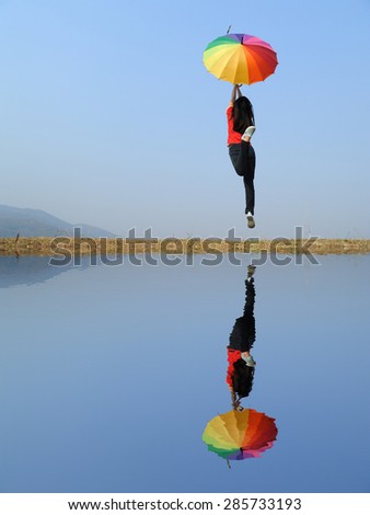 Water Reflection Rainbow umbrella woman and blue sky.Copy space