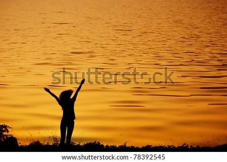 Happy woman jump and sunset silhouette in Lake