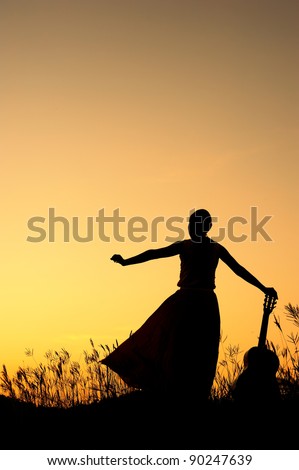Woman and guitar with sunset silhouette
