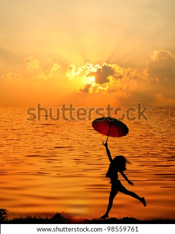 Umbrella woman jump and sunset silhouette in Lake