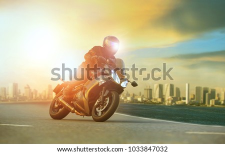 young man riding big motorcycle leaning on sharp curve with urban building background