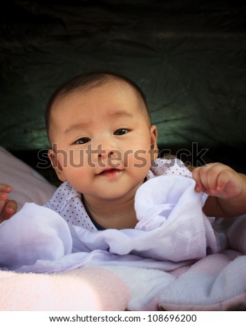 asian baby smiling face lied on bed