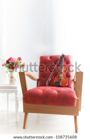 red leather wood arm chair with violin in white room