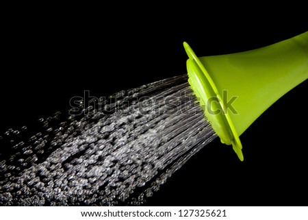 green watering can pouring water with high speed shutter isolated on black