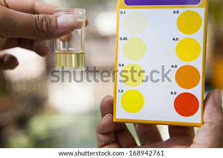 file hand holding chlorine  testing tube compared with chlorine color testing chart use for multipurpose science reserch and clean environment