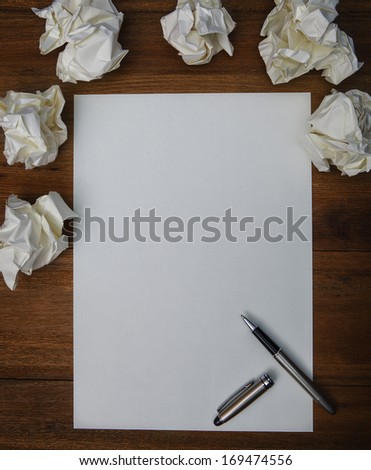 file of luxury pen ,white paper and crumpled paper on working  wood table use for idea creative of successful working hard to thinking about conceptual work flow