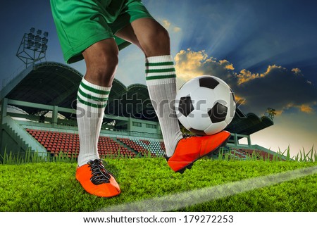 foot ball player holding foot ball on leg ankle in soccer sport field against stadium and dusky sky use for sport soccer football team competition match