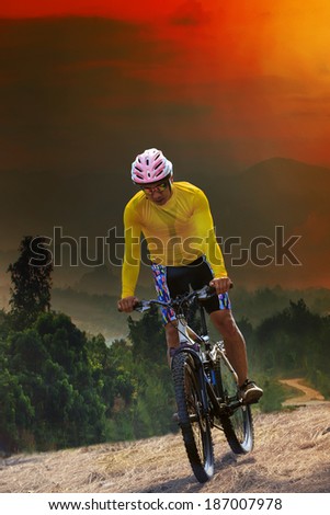 young man riding mountain bike bicycle crossing mountain hill jungle track with dusky sky scene use for out door sport and exteme activities lifestyle