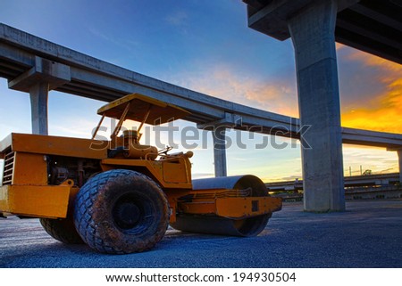bulldozer tank road construction machine against dusky sky and infra construction of express way