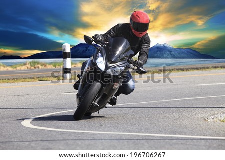 young man riding motorcycle in asphalt road curve with rural and mountain background