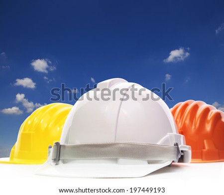 three of safety helmet construction protection on white against beautiful blue sky and white cloud with copy space
