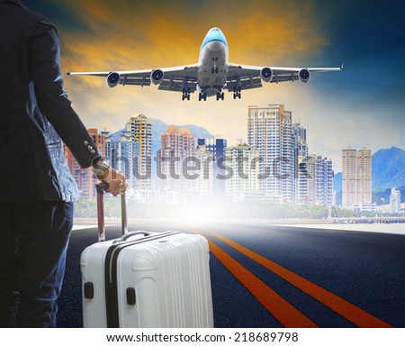business man and luggage standing on airport runways with passenger jet plane flying above airport runway use for aircraft transport ,traveling ,journey trip with airline