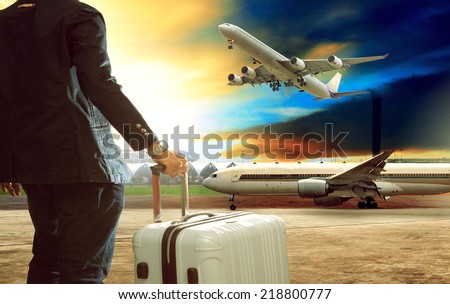 young business man standing with luggage suitcase in airport with jet plane flying above airport runway use for air transport and traveling business