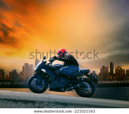young man and safety suit riding big motorcycle against beautiful dusky sky and urban scene with copy space