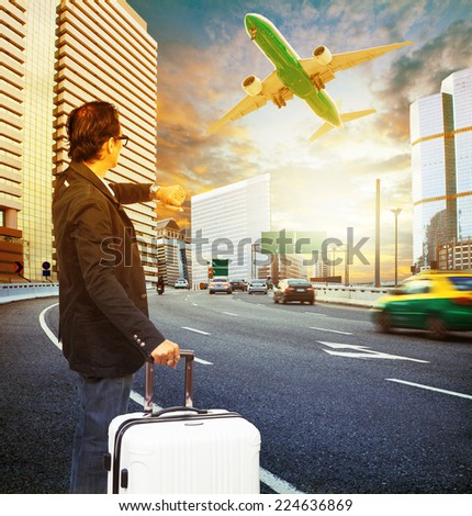 traveler man and luggage standing on traffic and looking to time watch against passenger car and airplane flying above