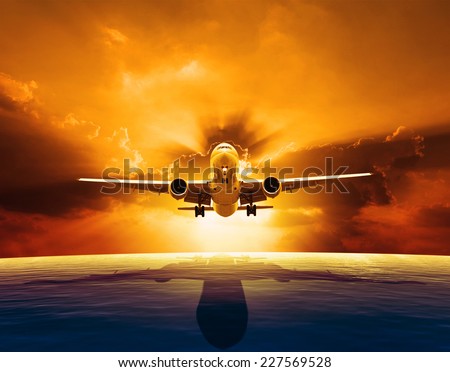 passenger jet plane flying over beautiful sea level with sun set sky above