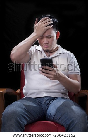 young asian man watching to smart phone screen with unhappy and worry ,serious face