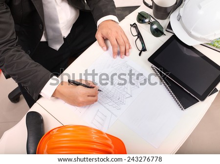 top view of architect working table with drawing perspective building plan and sunglasses ,safety helmet