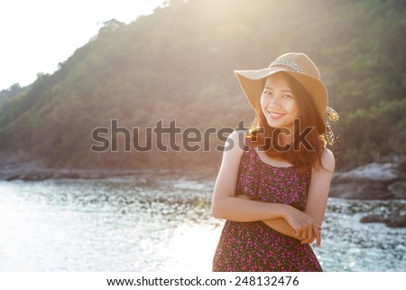 portrait of beautiful young woman wearing wide straw hat standing beside sea beach and toothy smiling face with happy emotion