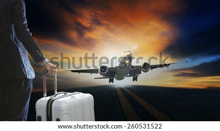 young business man and luggage suitcase standing with passenger plane take off from runways against beautiful dusky sky with copy space use for air transport ,journey and traveling industry business