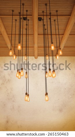 ceiling light bulb hanging on pine wood against warm tone of grungy cement wall use as home decorated background,backdrop and copy space