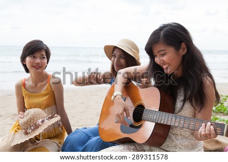 portrait group of young asian woman playing guitar in sea beach picnic party at sea side with happiness face emotion