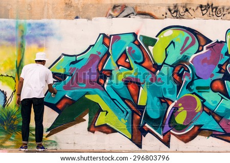 BANGKOK THAILAND : JULY 8 : young thai boy color spray bottle painting graffiti art on side road wall  in bangkok  thailand on july8 ,2015