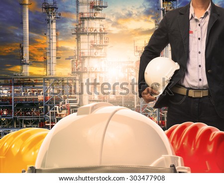 engineering man with white safety helmet standing in front of oil refinery building structure in heavy petrochemical industry