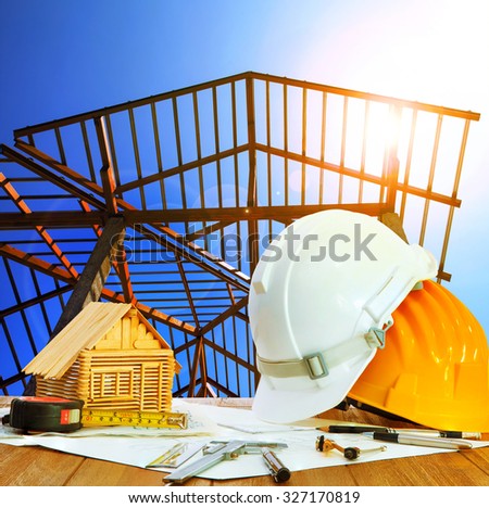 architect working table hard hat house model plan sheet and writing equipment against home roof structure construction site