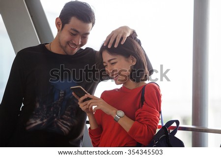 couples of younger asian man and woman relaxing with happy face reading text on smart phone use for people and modern lifestyle