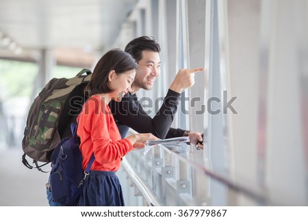 couples of younger traveling man and woman looking to traveler guide book on location