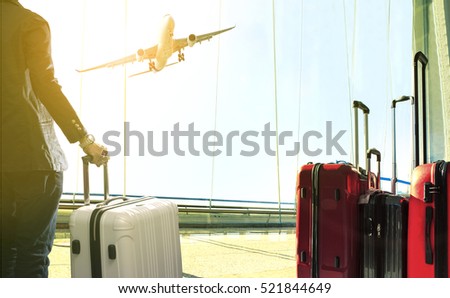 business man and stack of traveling luggage standing in airport terminal and passenger plane flying above