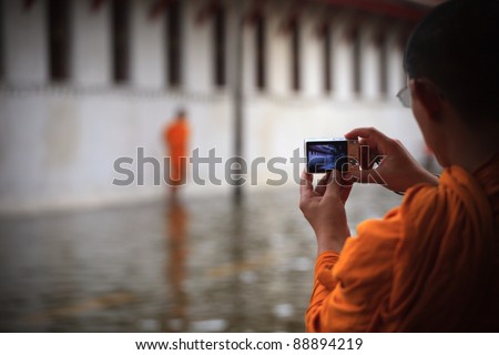 BANGKOK THAILAND - OCT 28 : Thai monk take a photograph of flood water at Tha Prachan Pier on Oct 28,2011 in Bangkok Thailand