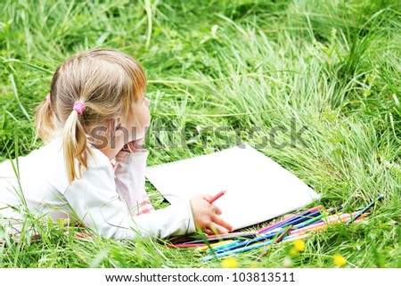 a beautiful little girl on the nature drawing pencils
