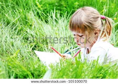 a beautiful little girl on the nature drawing pencils