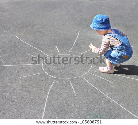 child draws with chalk on the pavement