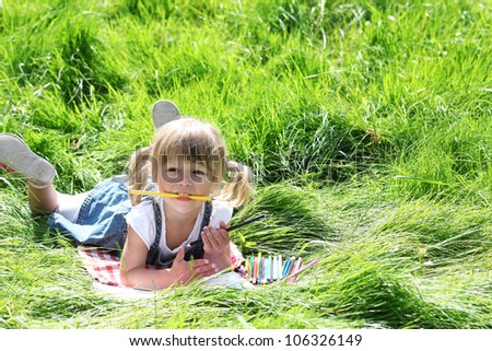 a beautiful little girl on the nature of drawing pencils