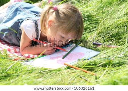 a beautiful little girl on the nature of drawing pencils