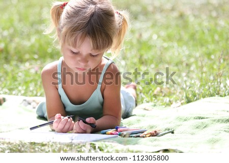 beautiful little girl drawing on nature