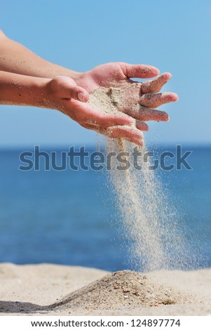 Hand throws sand on the seashore