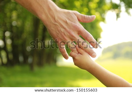 a hand of parent and child in nature