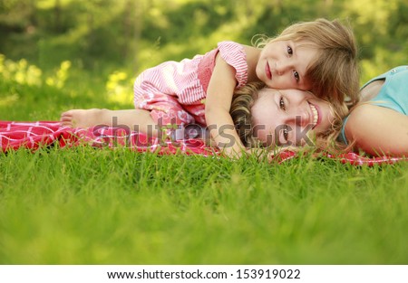 A Young Mother And Her Little Daughter Playing On Grass