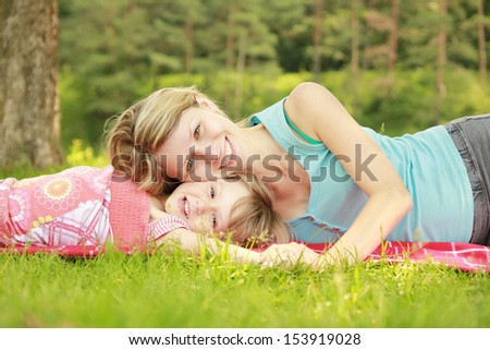 a young mother and her little daughter playing on grass