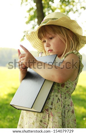 a little girl reading the Bible in nature